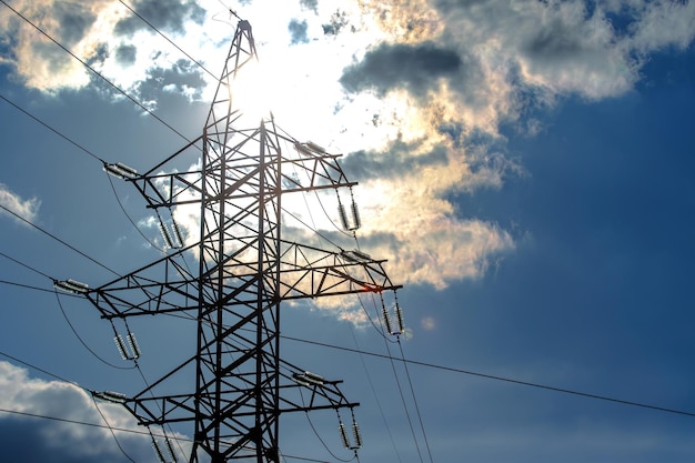 Torre de alta tensão com fios de energia contra o fundo do céu solar e nuvens O conceito de fonte de eletricidade Indústria de energia