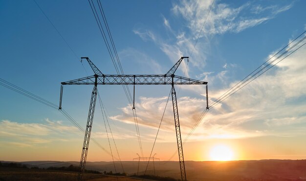 Torre de alta tensão com linhas de energia elétrica ao pôr do sol Transmissão de eletricidade