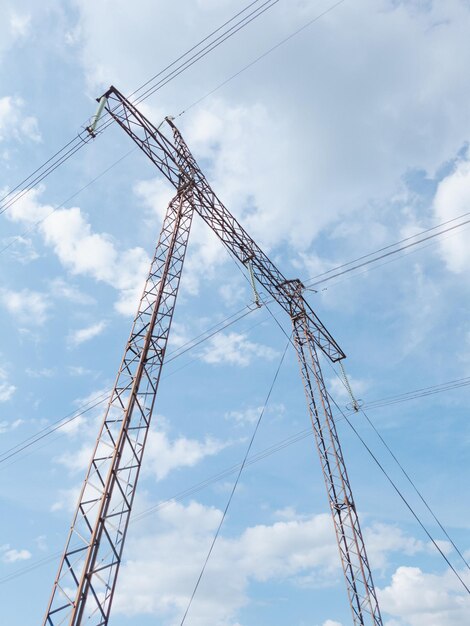 Torre de alta tensão de aço intermediária contra um fundo de céu nublado.