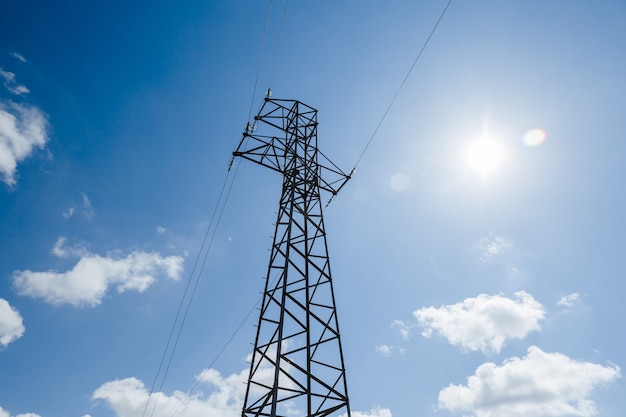 Torre de metal de alta tensão em um fundo de céu azul com fonte de alimentação de nuvens brancas