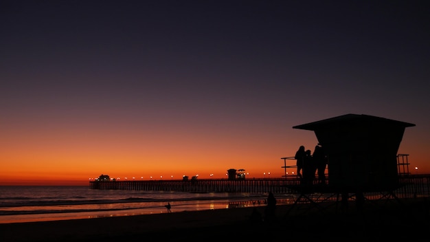 Torre de salva-vidas de meninas adolescentes, praia do oceano de amigos, pôr do sol ao anoitecer, Califórnia EUA. adolescentes