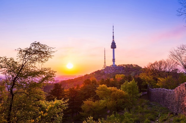 Torre de seul no pôr do sol e parede velha na montanha namsan