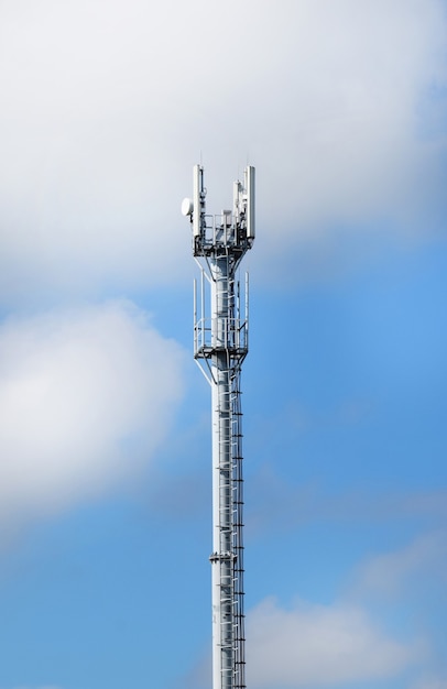 Torre de telecomunicações com antenas em um fundo de céu azul e nuvens. As antenas inteligentes transmitem sinais de celular 4G e 5G aos consumidores.