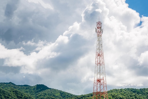 Torre de telecomunicações de telefonia móvel com nuvem branca e fundo de montanha de céu azul