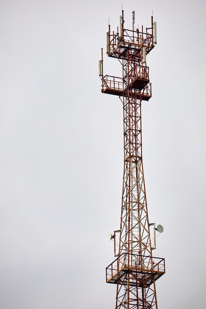 Torre de telefonia celular de telecomunicações com antenas móveis no fundo do céu azul