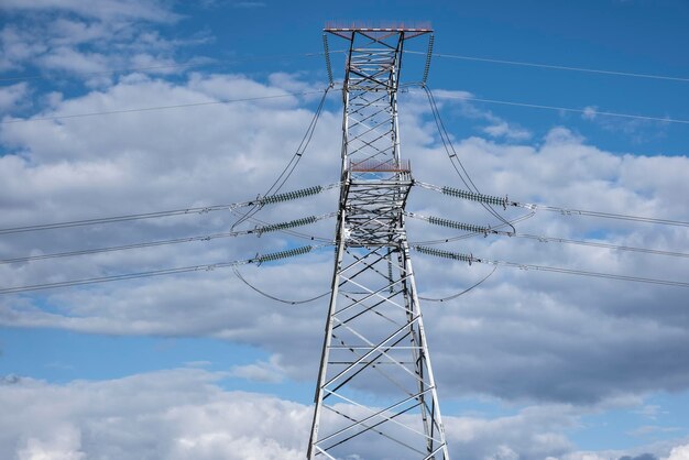 Torre de uma linha de energia de alta tensão contra o de céu azul e nuvens