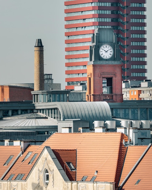 Foto torre do relógio contra o fundo de edifícios residenciais centro da cidade acima dos telhados