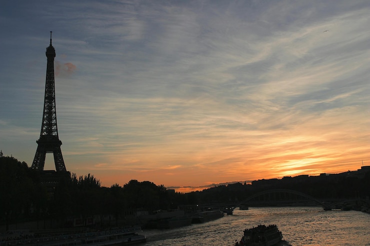 Foto la torre eiffel junto al río durante la puesta de sol