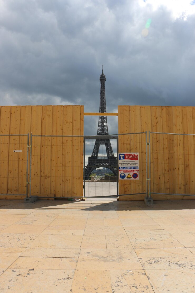 Foto la torre eiffel vista a través de una pared de madera contra un cielo nublado