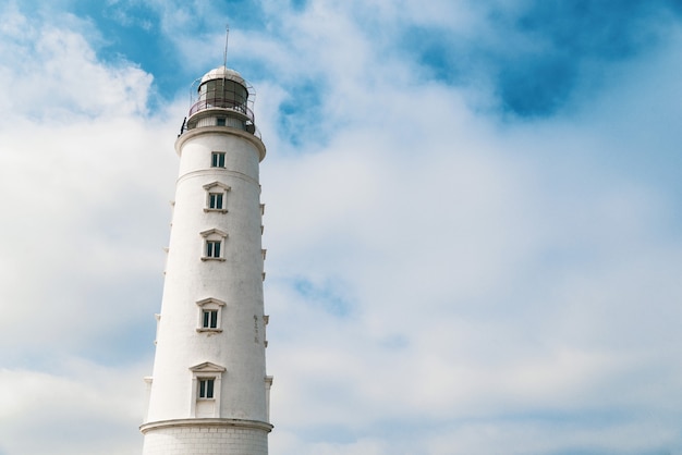 Torre del faro alto sobre un fondo de cielo nublado azul