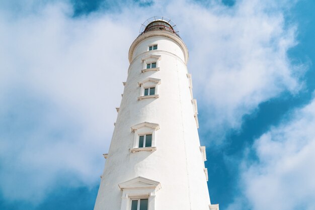 Foto torre del faro alto sobre un fondo de cielo nublado azul