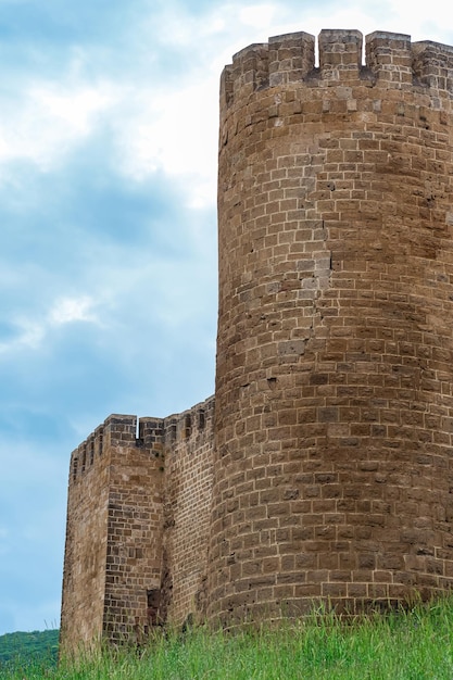 Torre de una fortaleza medieval sobre una muralla cubierta de hierba contra el cielo Ciudadela de NarynKala en Derbent