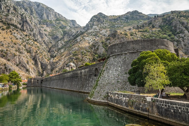 Torre Kampana y murallas de la fortaleza medieval con montañas y aguas verdes del río Scurda en primer plano Bahía de Kotor Montenegro