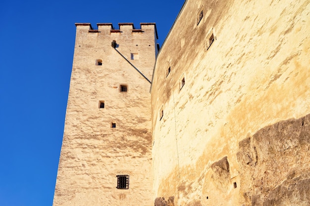 Torre y paredes del castillo de Salzburg Hohensalzburg en Austria. Paisaje y paisaje urbano de la fortaleza de piedra en la ciudad de Mozart en Europa. Vista del antiguo fuerte en la ciudad austriaca de Salzburgerland. Cielo azul