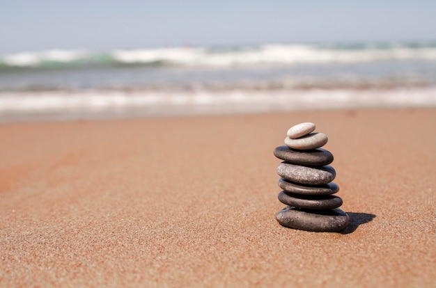 Torre de piedras de guijarros en la playa de arena. Concepto de equilibrio de zen