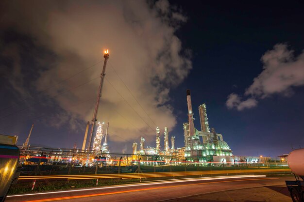 Torre de refinería de petróleo flare fuego de la industria petroquímica en la noche del cielo nuboso