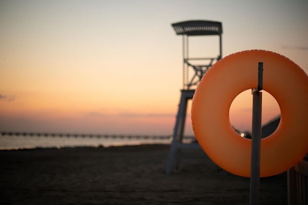 Torre de rescate de salvavidas naranja en la playa Nadar al atardecer y de noche Comportamiento seguro en el agua para niños y adultos Clima cálido mar en calma