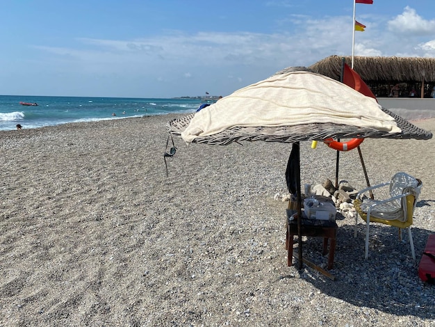 Torre salva-vidas com guarda-sol e bóia salva-vidas na praia de areia no mar de férias em calor turístico