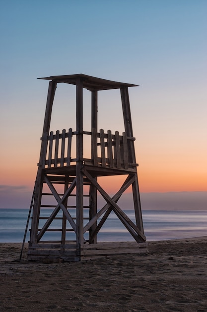 Una torre de salvavidas en la playa mediterránea al atardecer durante el verano