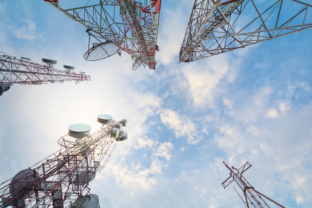 Torre de la telecomunicación con las antenas con el cielo azul en la luz del sol de la mañana.