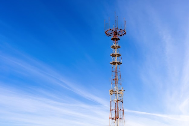 Torre de telecomunicaciones para televisión, radio y teléfono contra el cielo azul con hermosas nubes blancas