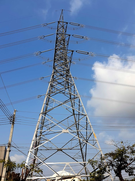 Torre de transmisión eléctrica de alto voltaje en las nubes en el fondo del cielo azul