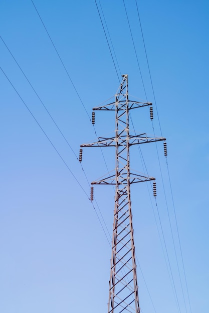 Torre de transmisión eléctrica sobre fondo vertical de cielo azul