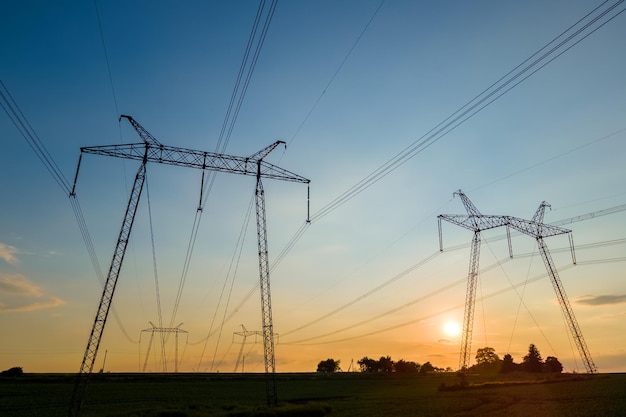 Torres de alta tensión con líneas eléctricas al atardecer.