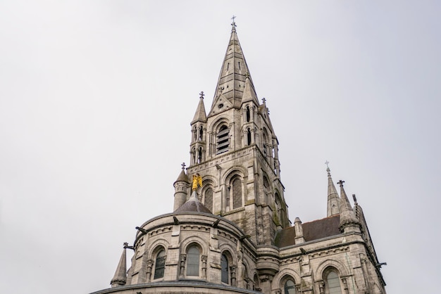 Torres y ángel de oro de la catedral de Cork en el sur de Irlanda un típico día gris del país