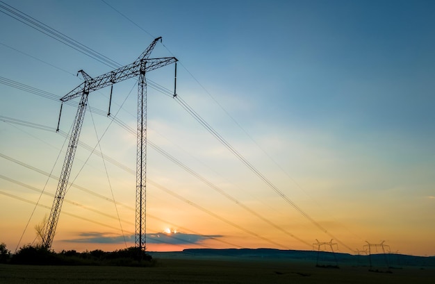 Torres de alta tensão com linhas de energia elétrica ao pôr do sol