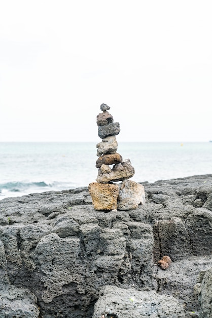 Torres de pedra em rochas basálticas na praia de hyeopjae, ilha de jeju