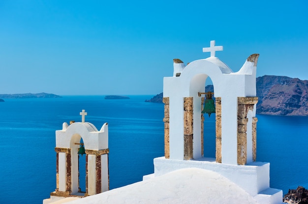 Torres do sino da igreja ortodoxa grega acima do mar na ilha de Santorini, Grécia