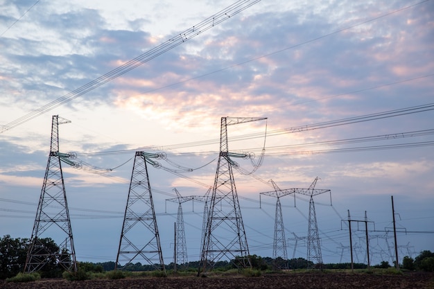 Torres eléctricas y líneas eléctricas de alta tensión al atardecer silueta de grupo de fondo de transmisión