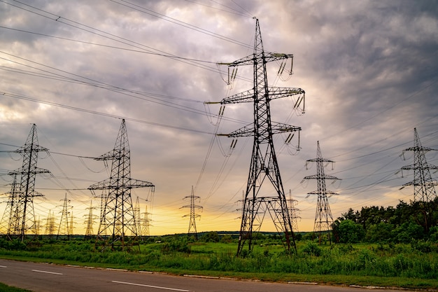 Torres de electricidad y líneas eléctricas de alta tensión sobre la hierba verde. Planta de energía. Red de energía eléctrica. Vista desde abajo.