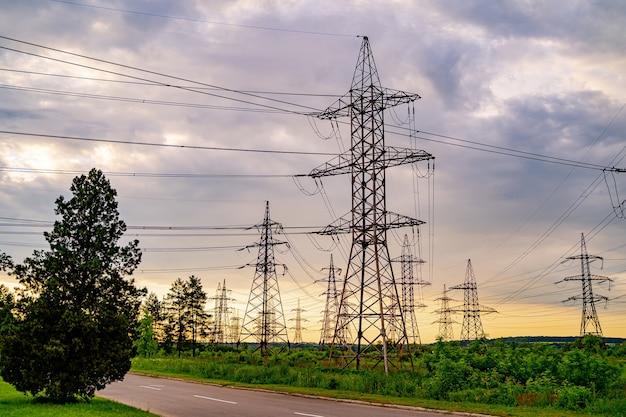 Torres de electricidad que llevan la fuente de alimentación a través de un paisaje rural durante la puesta de sol. Enfoque selectivo.