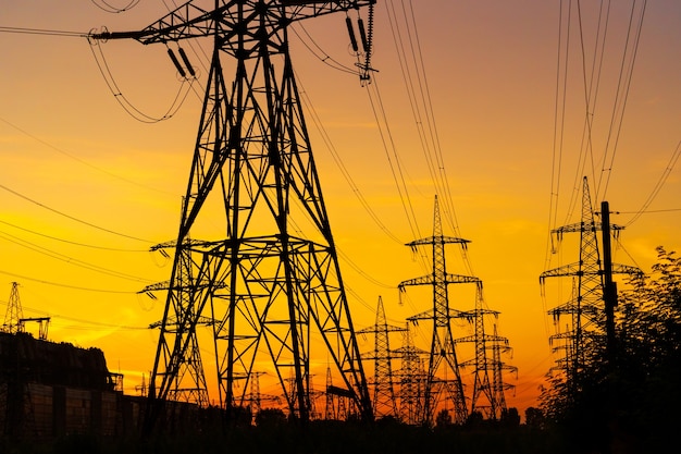 Torres de electricidad que llevan la fuente de alimentación a través de un paisaje rural durante la puesta de sol