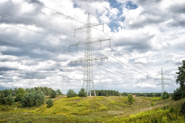 Torres de energía en el paisaje natural. Torres de transmisión en cielo nublado. Estructura de torre de electricidad con líneas eléctricas. Poste de alto voltaje al aire libre. Energía y ecología.