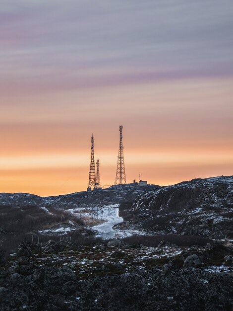 Torres de telefonía móvil en las colinas nevadas de la tundra. Hermoso paisaje montañoso al atardecer del Ártico