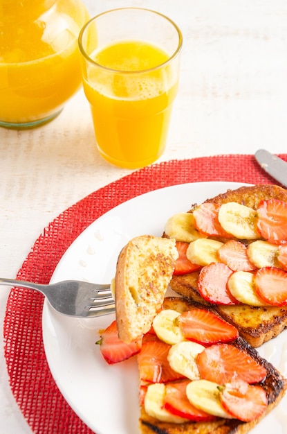 Torrija con fresas, plátano y miel Zumo de naranja Fondo blanco