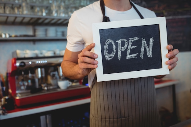 Foto torso de camarero con pizarra en café