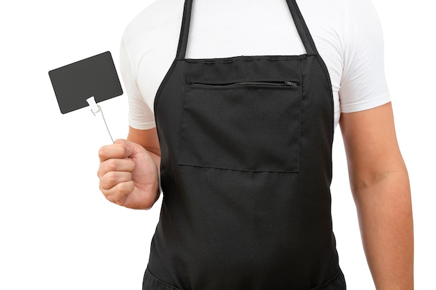 Torso de un cocinero masculino en un delantal negro con una etiqueta de precio en la mano sobre un fondo blanco.