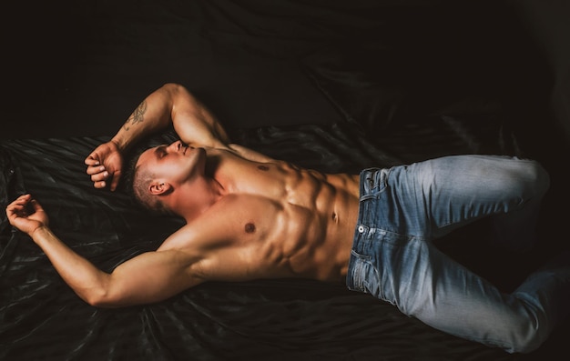 Torso masculino musculoso abs desnudo hombre acostado en la cama chico sexy en el dormitorio