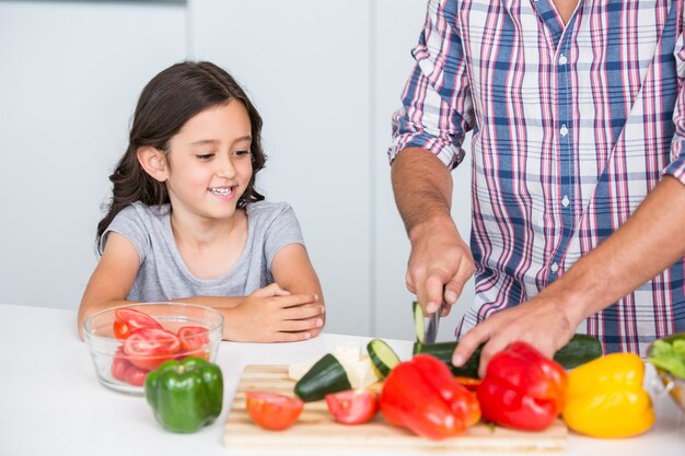 Torso de padre cortando verduras con hija