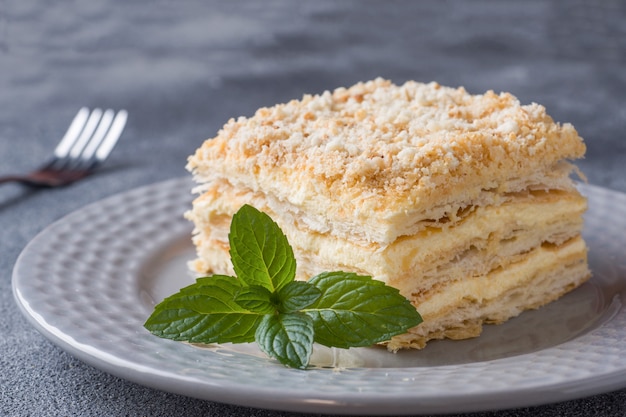 Foto torta acodada con milhojas de vainilla de napoleón crema rebanada con menta en la oscuridad