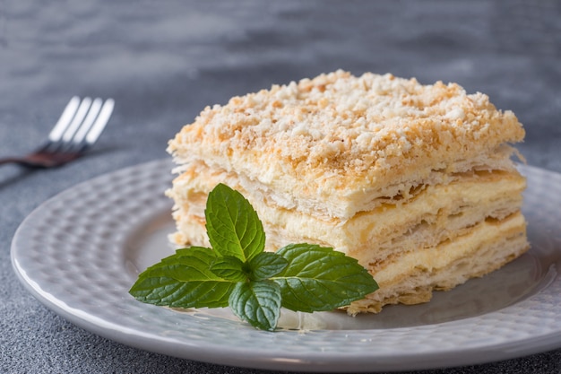 Torta acodada con milhojas de vainilla de Napoleón crema rebanada con menta en la oscuridad