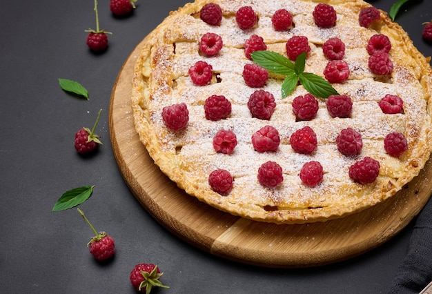 Torta assada redonda com maçãs e polvilhada com açúcar de confeiteiro em uma mesa preta