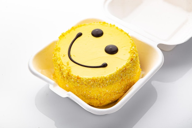 Torta bento con patrón de cara sonriente y corazones en caja de plástico.