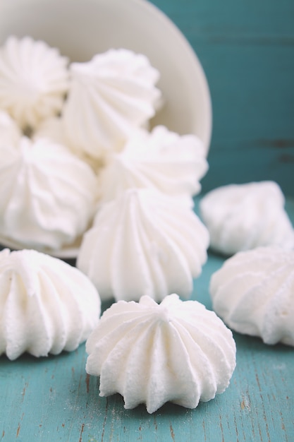 Torta blanca del merengue dispersada en un fondo de madera azul