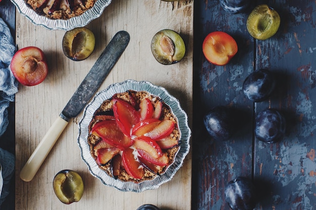 Torta caseira de ameixas orgânicas frescas na placa de madeira e mesa rústica Comida vegetariana saudável sazonal sobremesa outono vista superior foco seletivo