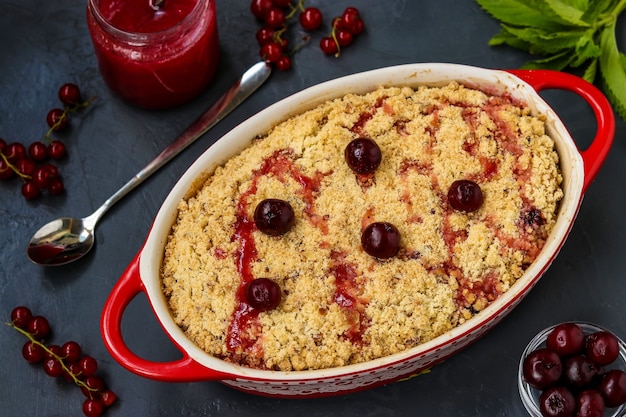 Torta caseira de cereja fresca com farinha de trigo integral em cerâmica em um fundo escuro, pronta para comer, closeup, foto horizontal